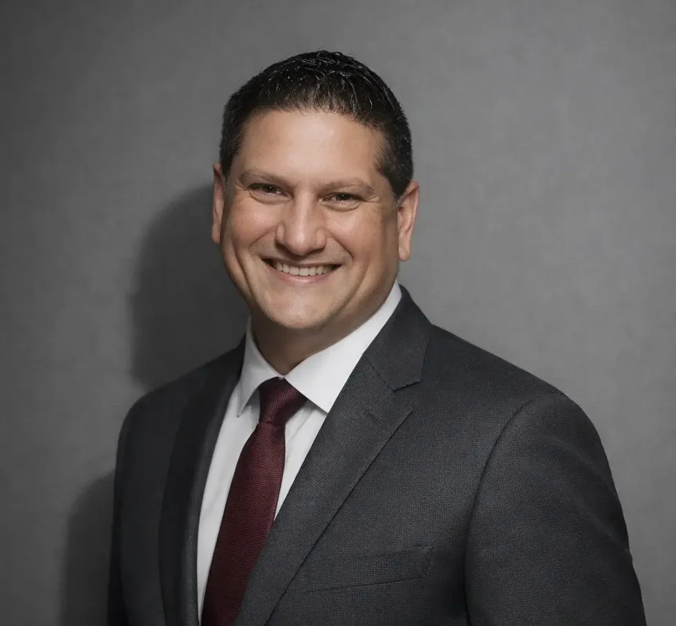 Milan Headshot in a business suit grey wall